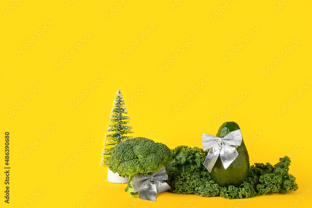 Composition with green vegetables and Christmas decor on yellow background