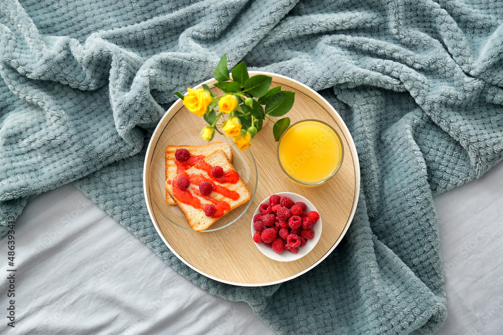 Tray with breakfast and flowers on soft plaid