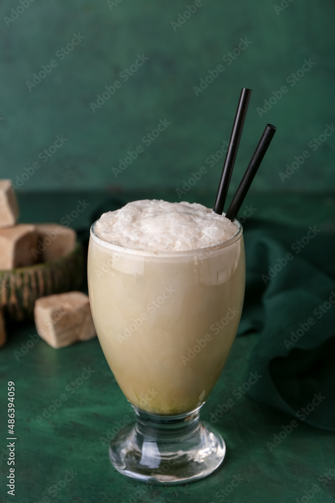 Glass of iced hojicha latte on green background