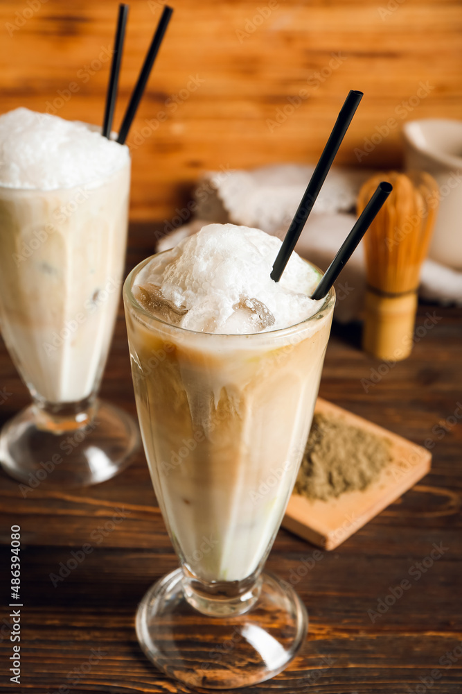 Glass of tasty iced hojicha latte on wooden table, closeup