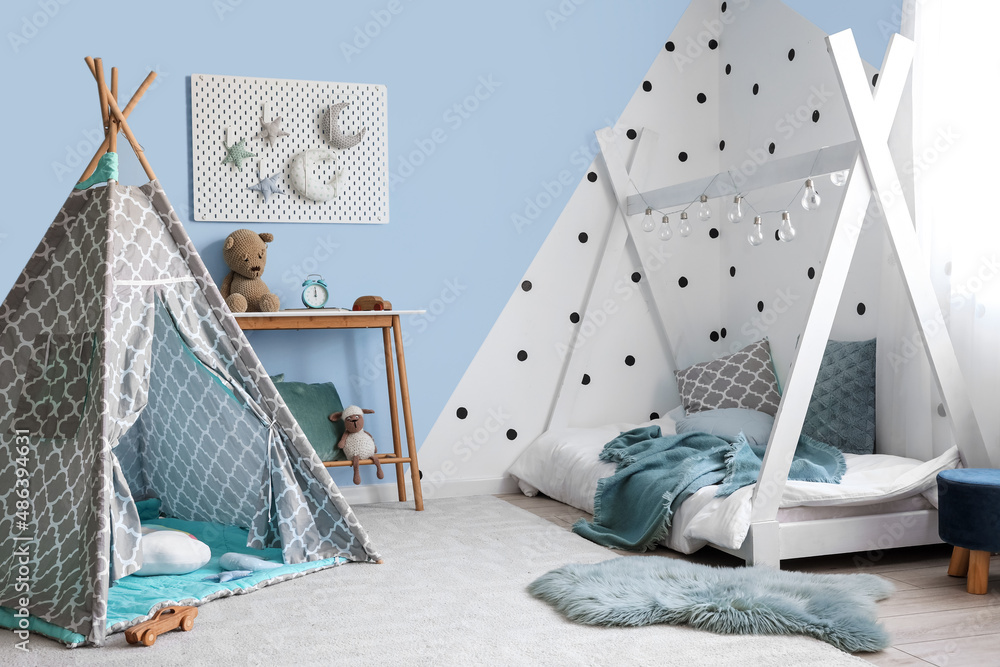 Interior of stylish childrens bedroom with play tent and pegboard