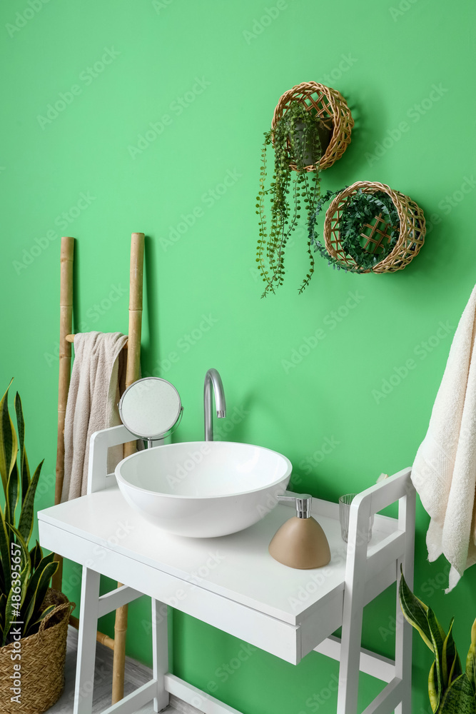 Interior of stylish bathroom with white table, sink and ladder