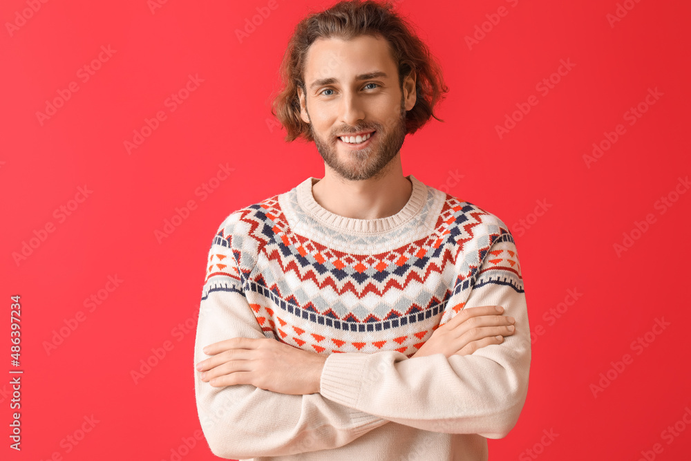 Handsome young man in knitted sweater on color background