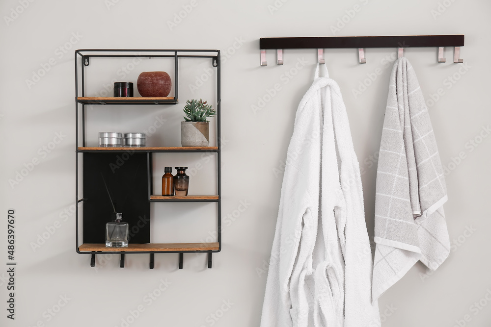 Rack and shelves with bath accessories hanging on light wall