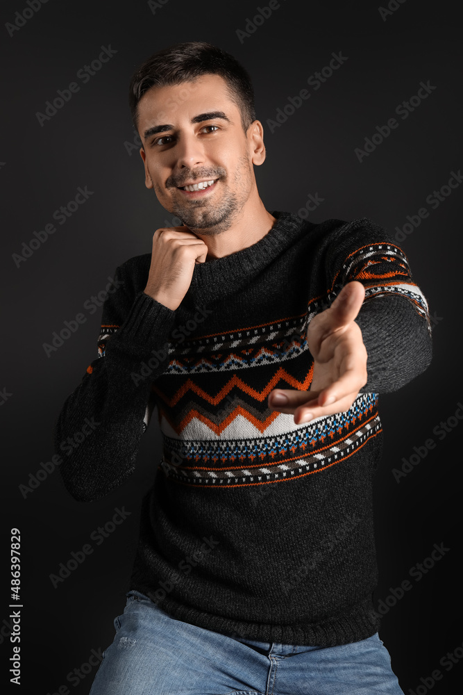 Handsome young man in knitted sweater on dark background