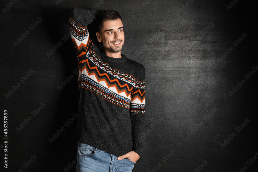 Handsome young man in knitted sweater on dark background