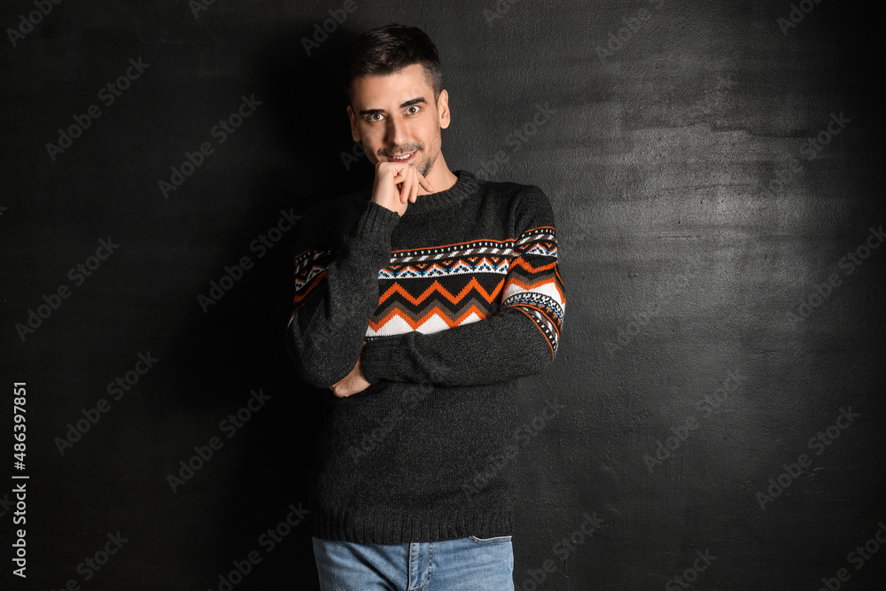 Handsome young man in knitted sweater on dark background