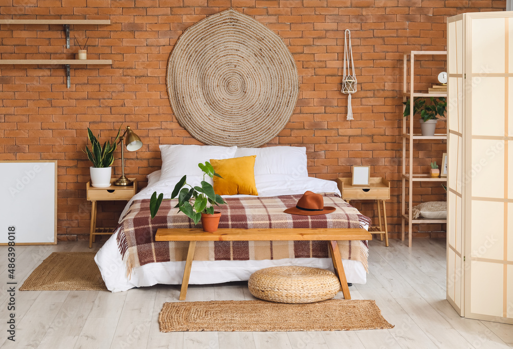 Interior of stylish bedroom with folding screen and wooden bench