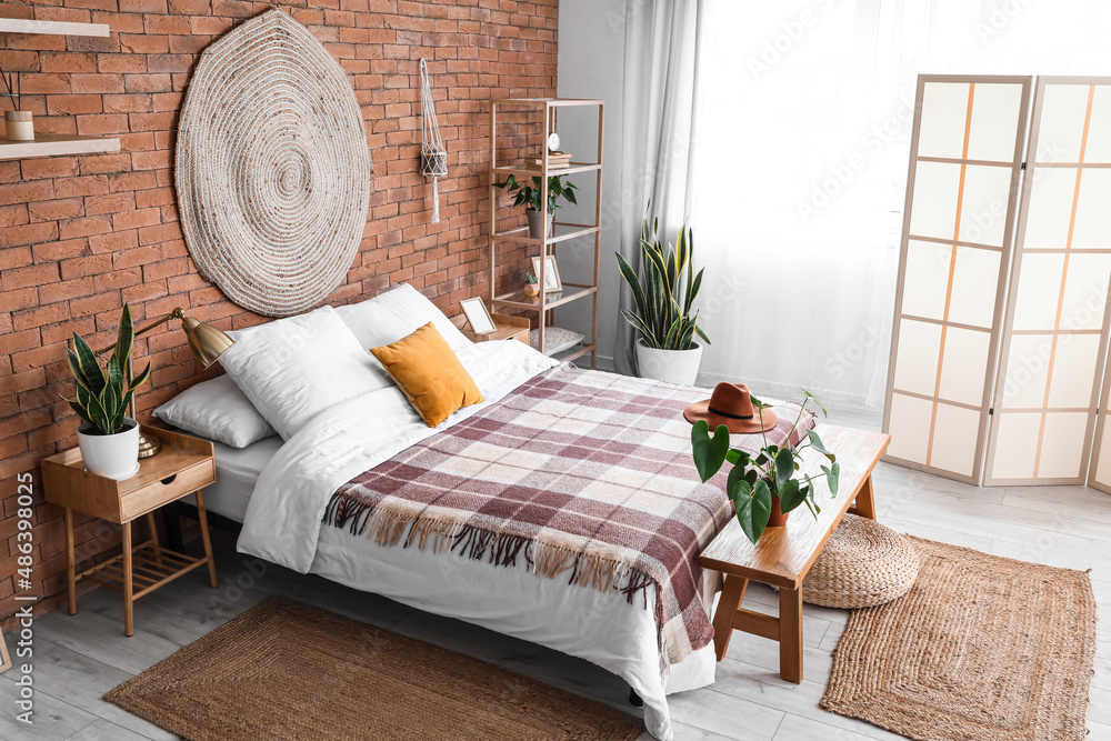 Interior of stylish bedroom with folding screen and houseplants