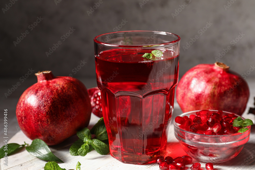 Glass of delicious pomegranate juice and fresh fruits on table