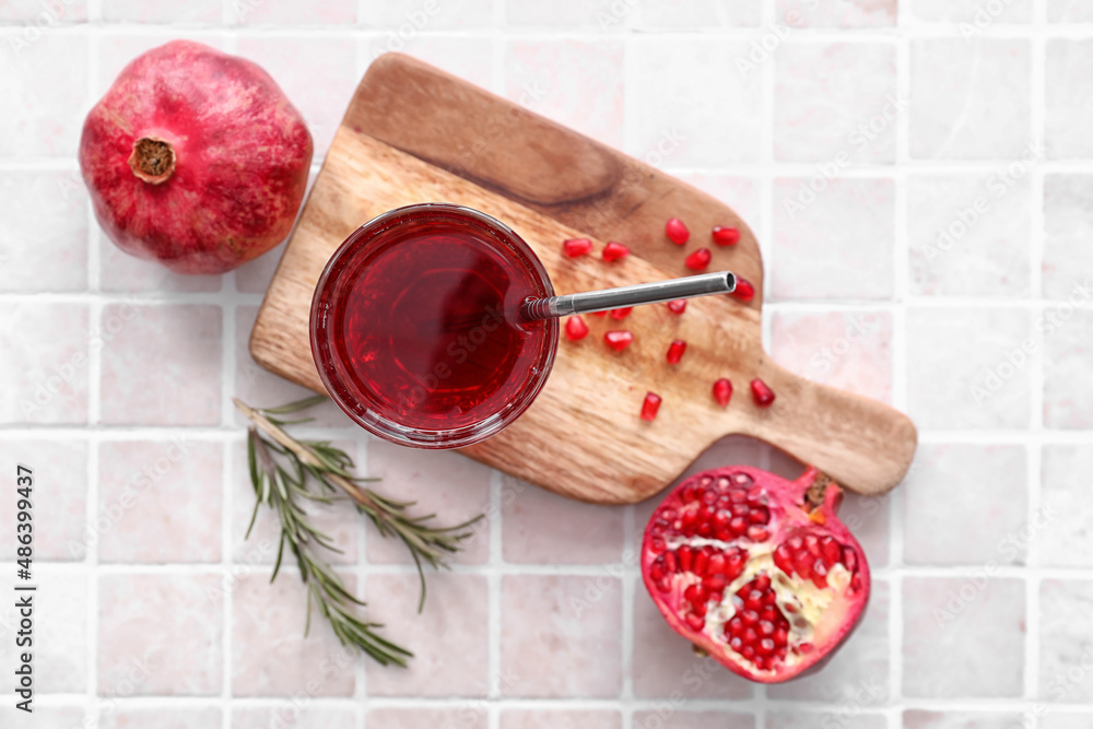 Glass of delicious pomegranate juice on tile background