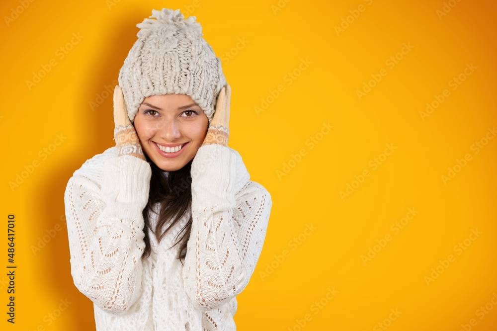 Happy playful young woman smiles keep hands-on hat dressed