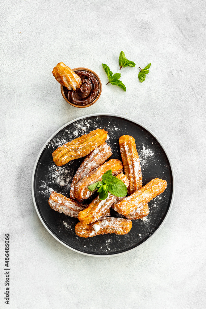 Fried churros with chocolate sauce and mint. Spanish sweets for breakfast