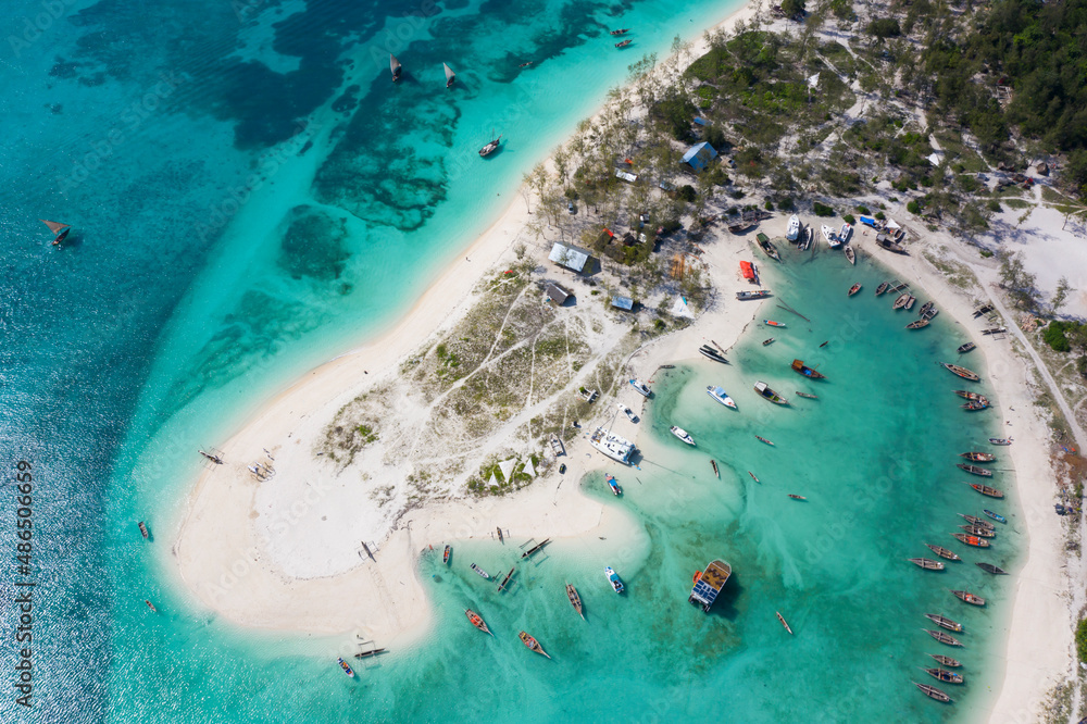 Aerial view of lagoon with white sandy coast, turquoise water of ocean and many boats. Drone photo