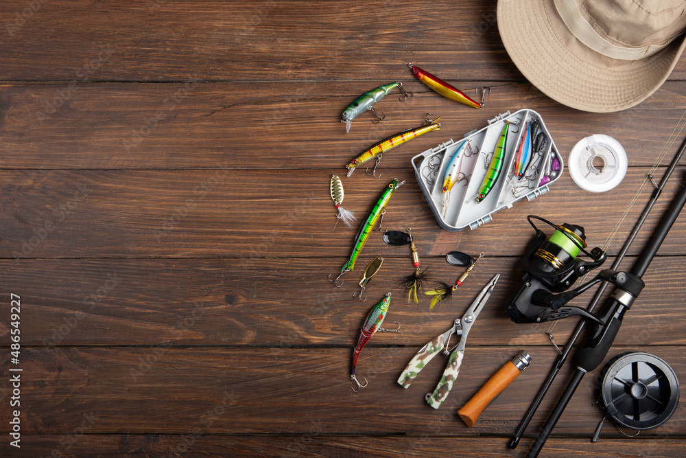 Fishing tackle - fishing spinning rod, hooks and lures on wooden background. Active hobby recreation