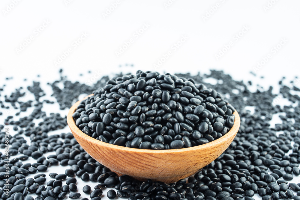 A bowl of small black beans on a white background