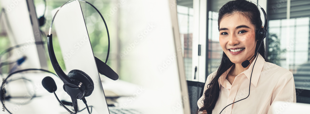 Businesswoman wearing headset working actively in office . Call center, telemarketing, customer supp