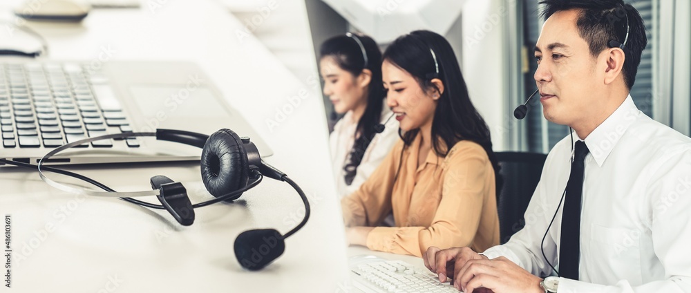 Business team wearing headset working actively in office . Call center, telemarketing, customer supp