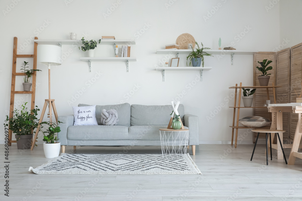 Stylish grey sofa in modern interior of living room