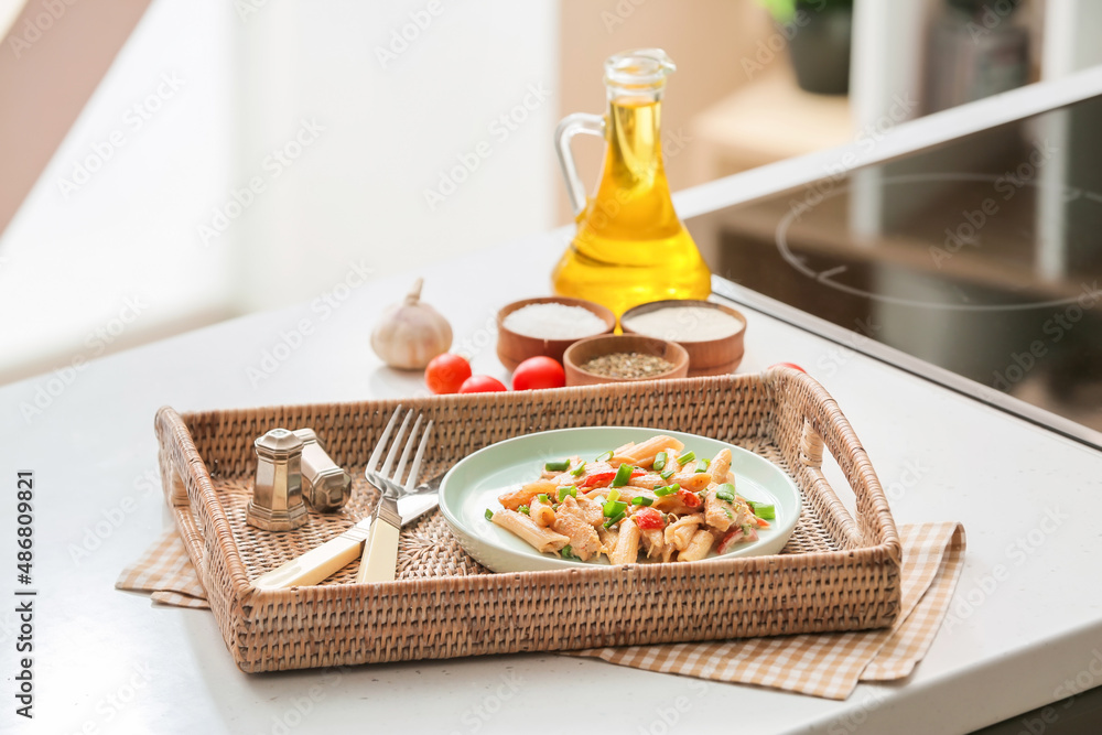 Tray with cajun chicken pasta on table in kitchen