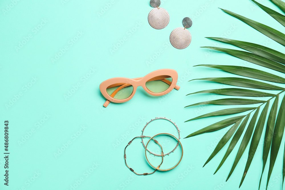 Composition with beautiful female accessories and palm leaf on color background