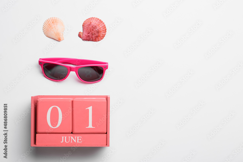 Calendar with date JUNE 1, sunglasses and seashells on white background