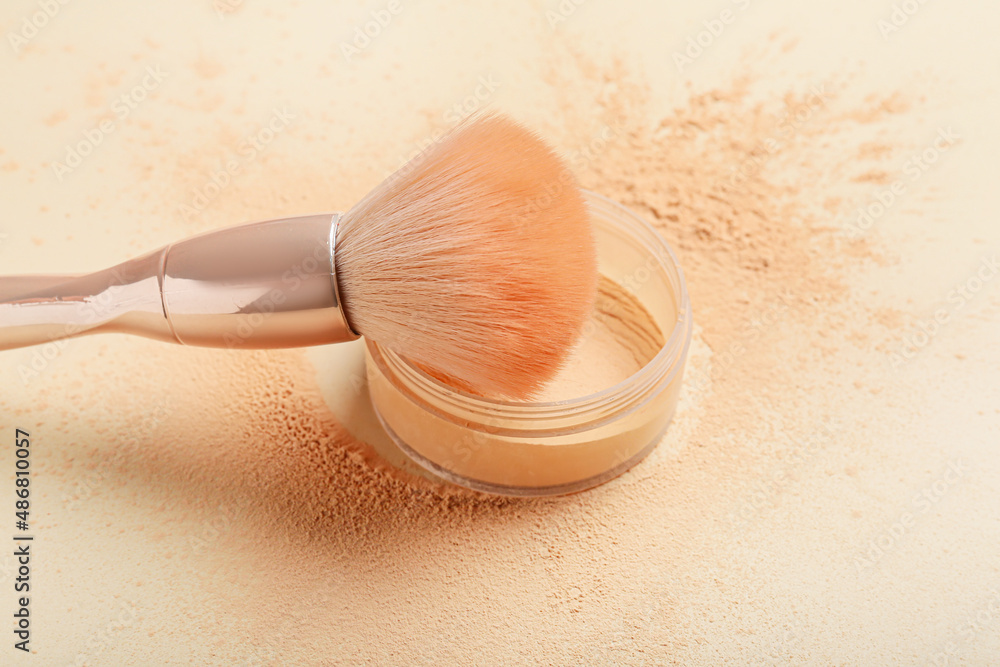 Makeup brush and loose powder on light background