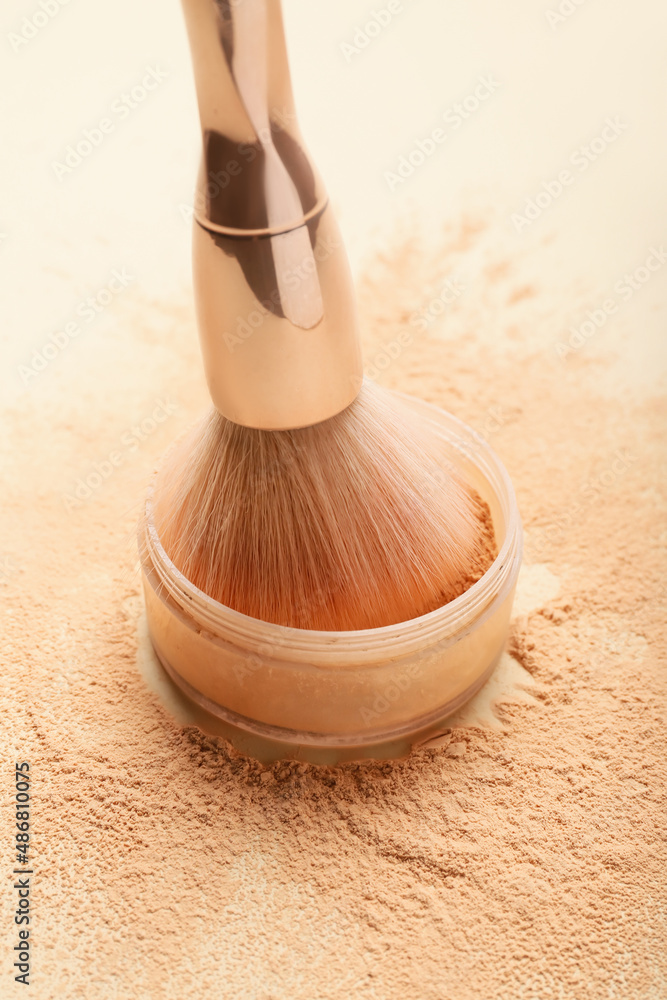 Makeup brush and loose powder on light background