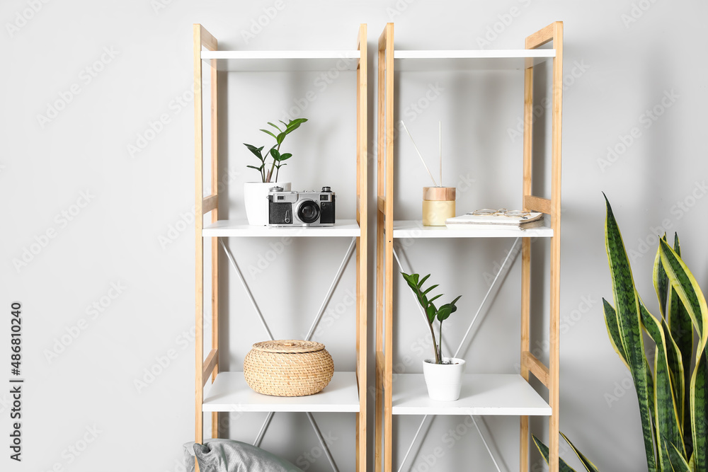 Shelving unit with photo camera and decor near light wall