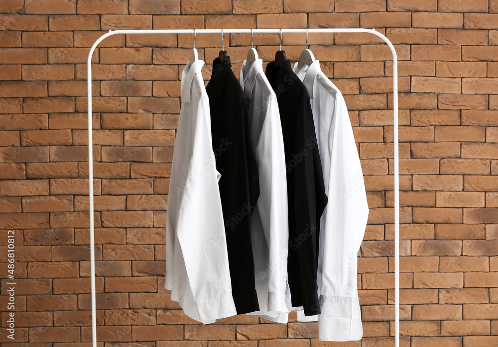 Rack with clean shirts near brick wall