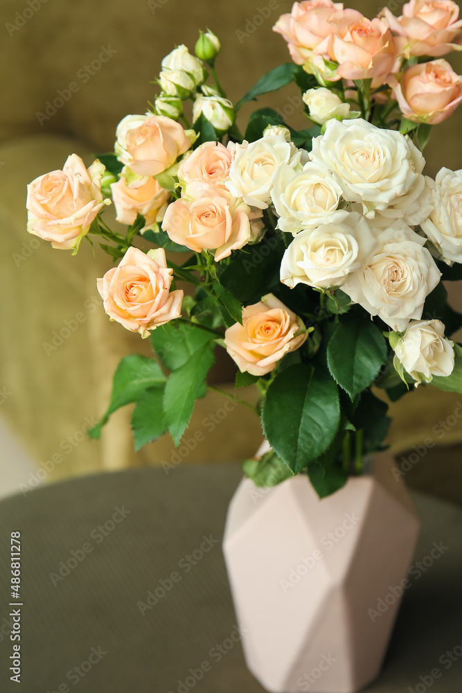 Vase with bouquet of beautiful fresh roses on table in room