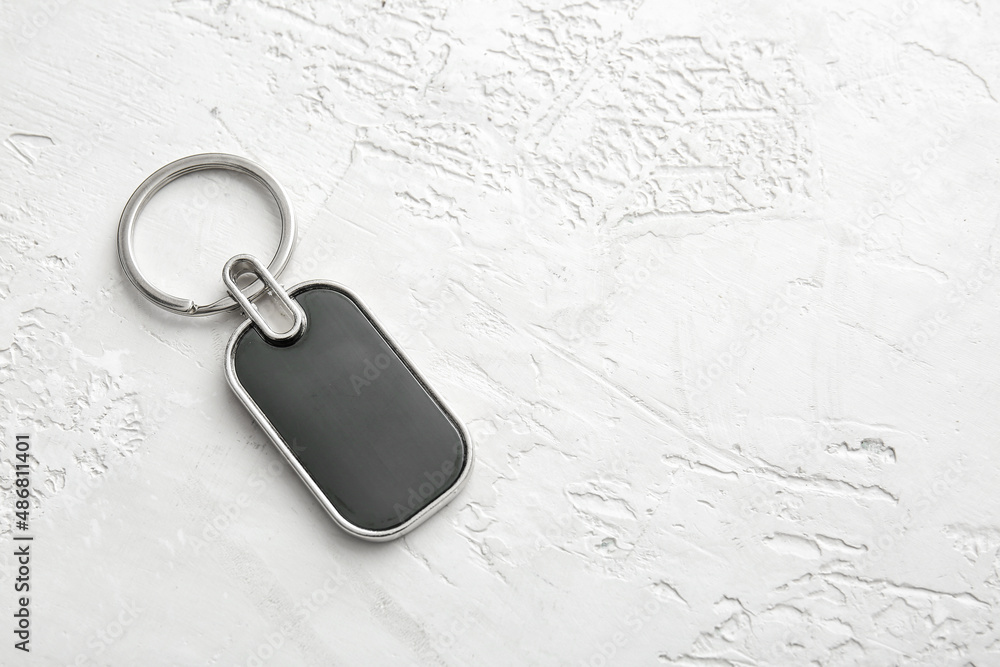 Stylish metalLic keychain on light background