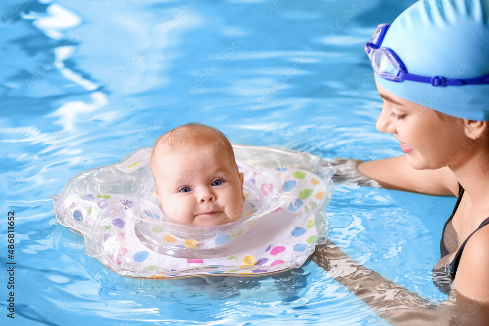 Young mother and her adorable baby with inflatable ring in swimming pool