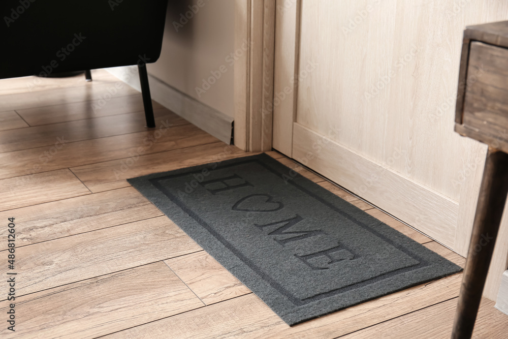 Modern mat near light wooden door in hall, closeup