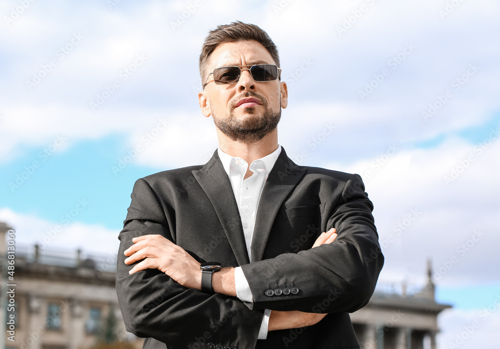 Stylish businessman in sunglasses on city square