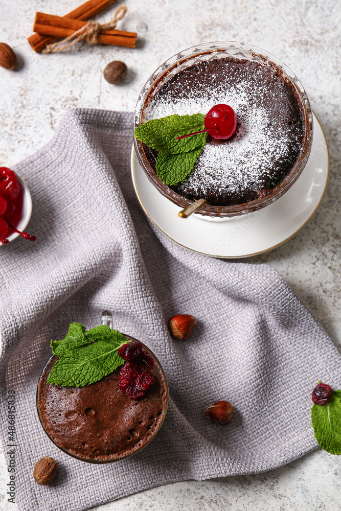 Glass bowl and cup with tasty chocolate brownie on light background