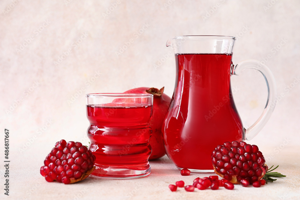 Jug and glass of delicious pomegranate juice on white background