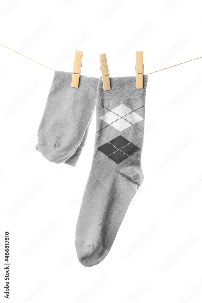 Male socks hanging on rope against white background