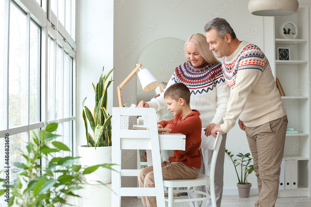 Little boy with his grandparents in warm sweaters using laptop at home