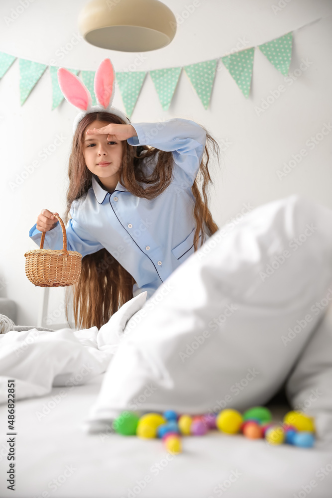 Cute little girl looking for Easter eggs in bedroom