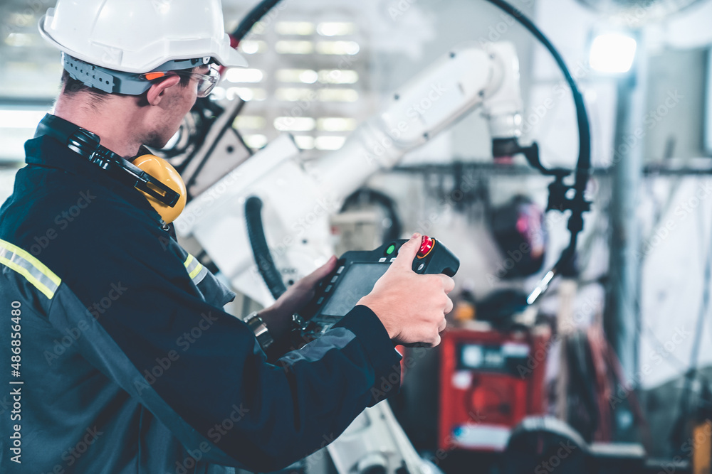 Young factory worker working with adept robotic arm in a workshop . Industry robot programming softw