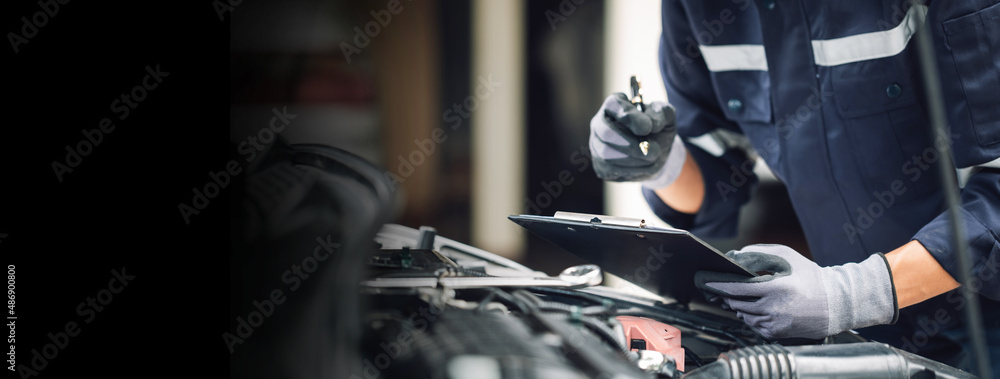 Car service, repair, maintenance concept,auto mechanic man or Smith writing to the clipboard at work