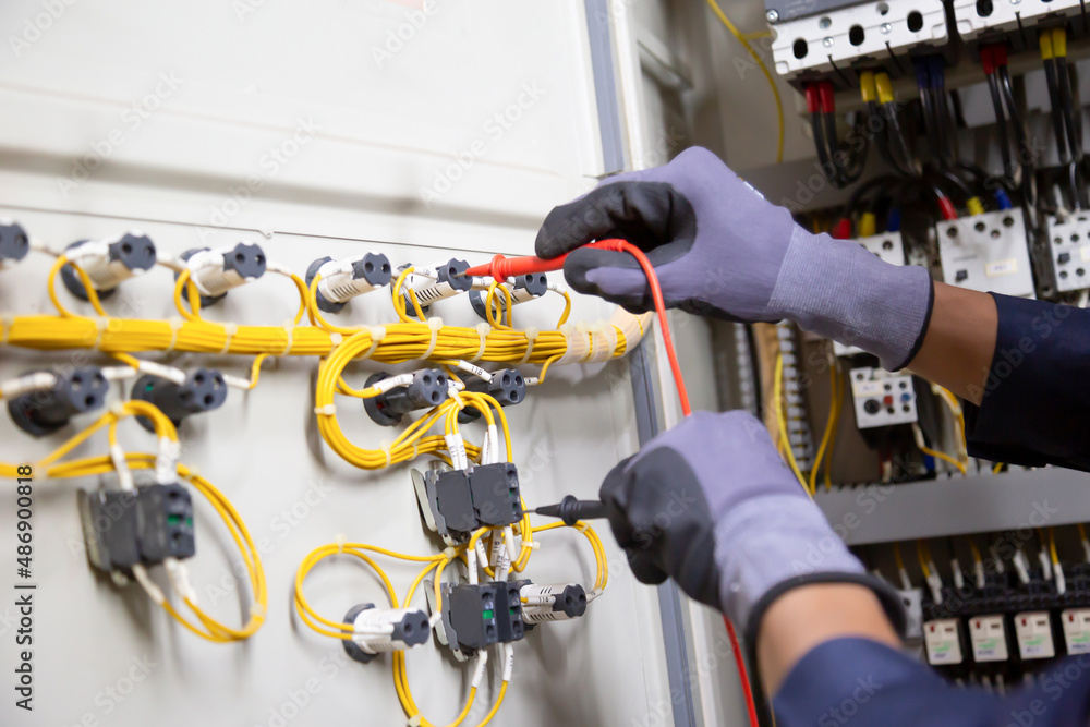 Electrician engineer tests electrical installations and wires on relay protection system. Adjustment