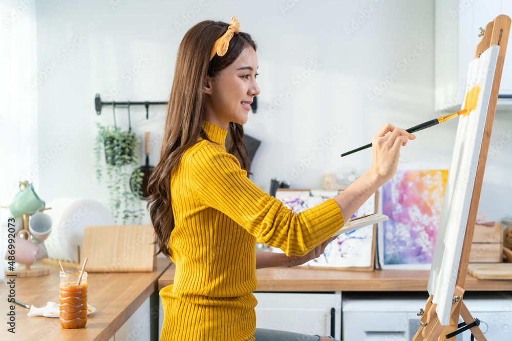 Asian young talented woman artist coloring on painting board in house. 