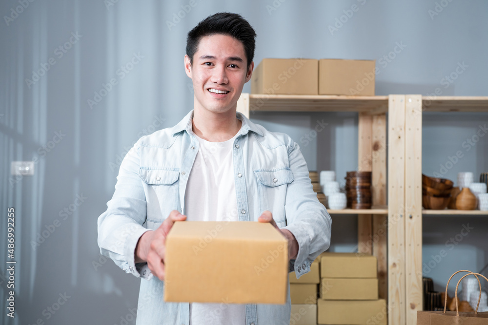 Portrait of Asian young businessman handing product order to customer. 