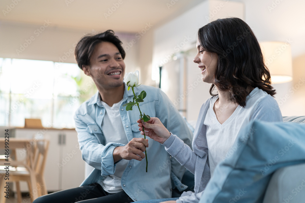 Asian young man surprise and give rose flower to beautiful girlfriend.