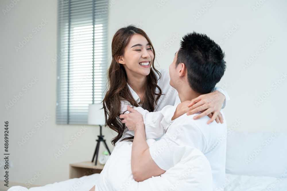 Asian new marriage couple sit on bed and look at each other with love. 