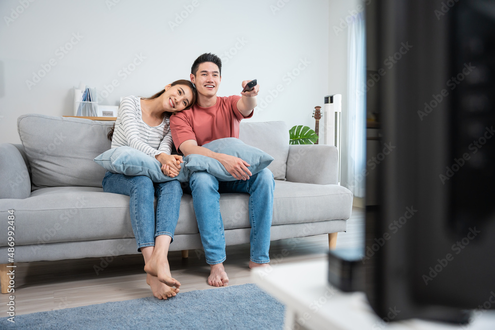 Asian young loving couple watch movie together in living room at home. 