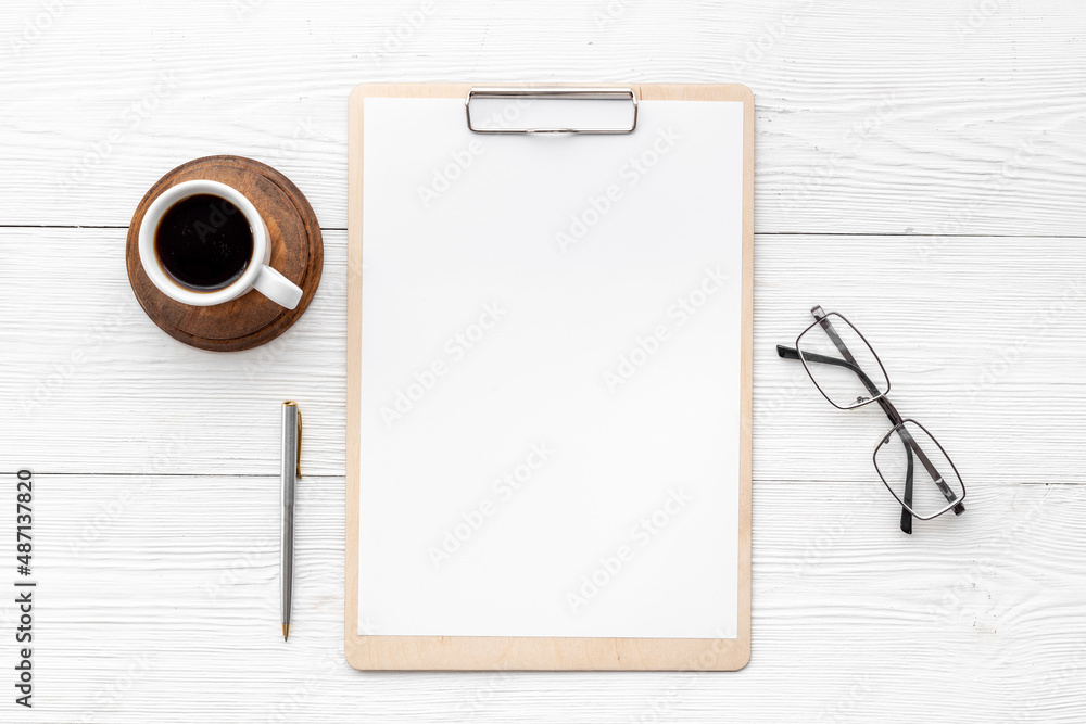 White office desk table with empty paper on clipboard