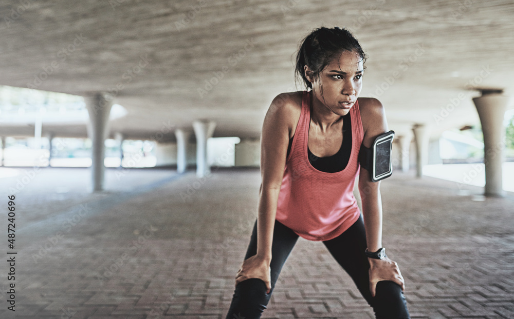 Youve gotta sweat for it. Shot of a sporty young woman taking a break while exercising outdoors.